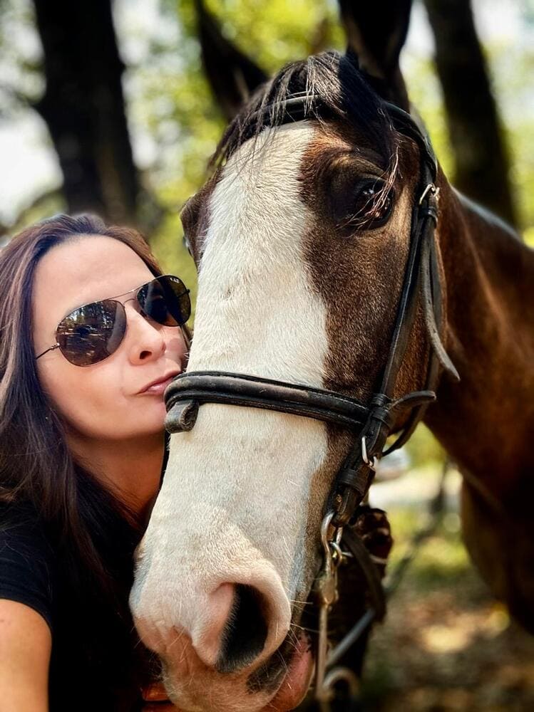 Cabeza de mujer cercana a cabeza de caballo casi dándole un beso